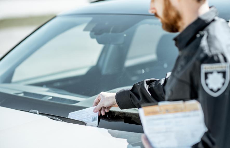 Agent posant une amende de stationnement sur le pare-brise d'une voiture - article amende de stationnement par Maître Franck Cohen
