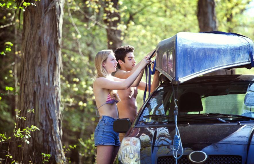 Photo d'un couple installant un canoë sur le toit de leur voiture. L'homme est torse nu. Article sur conduire torse nu par Maître Franck Cohen