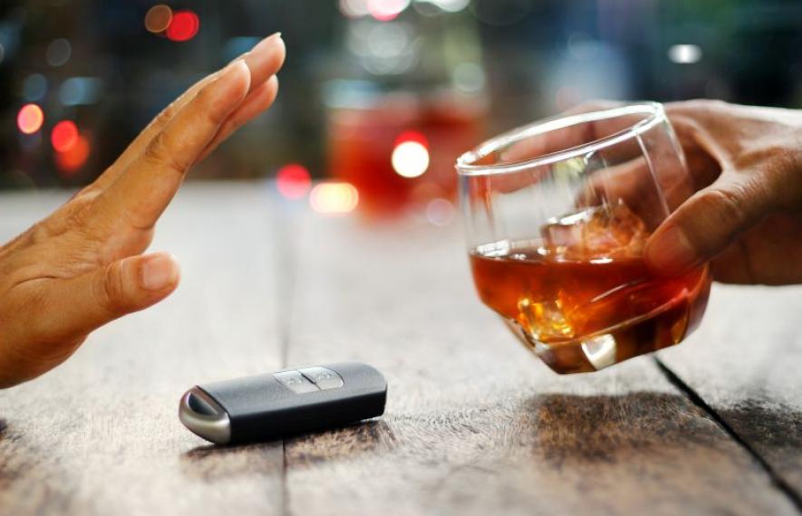 Main tendue pour refuser un verre d'alcool placé à côté d'une clé de voiture, illustrant le message de prévention contre la conduite en état d'ivresse.