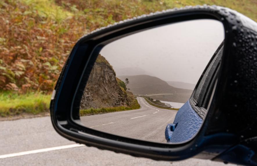 Gros plan sur le rétroviseur d'une voiture montrant le paysage d'une route de bord de mer