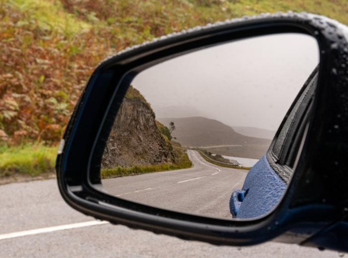 Gros plan sur le rétroviseur d'une voiture montrant le paysage d'une route de bord de mer